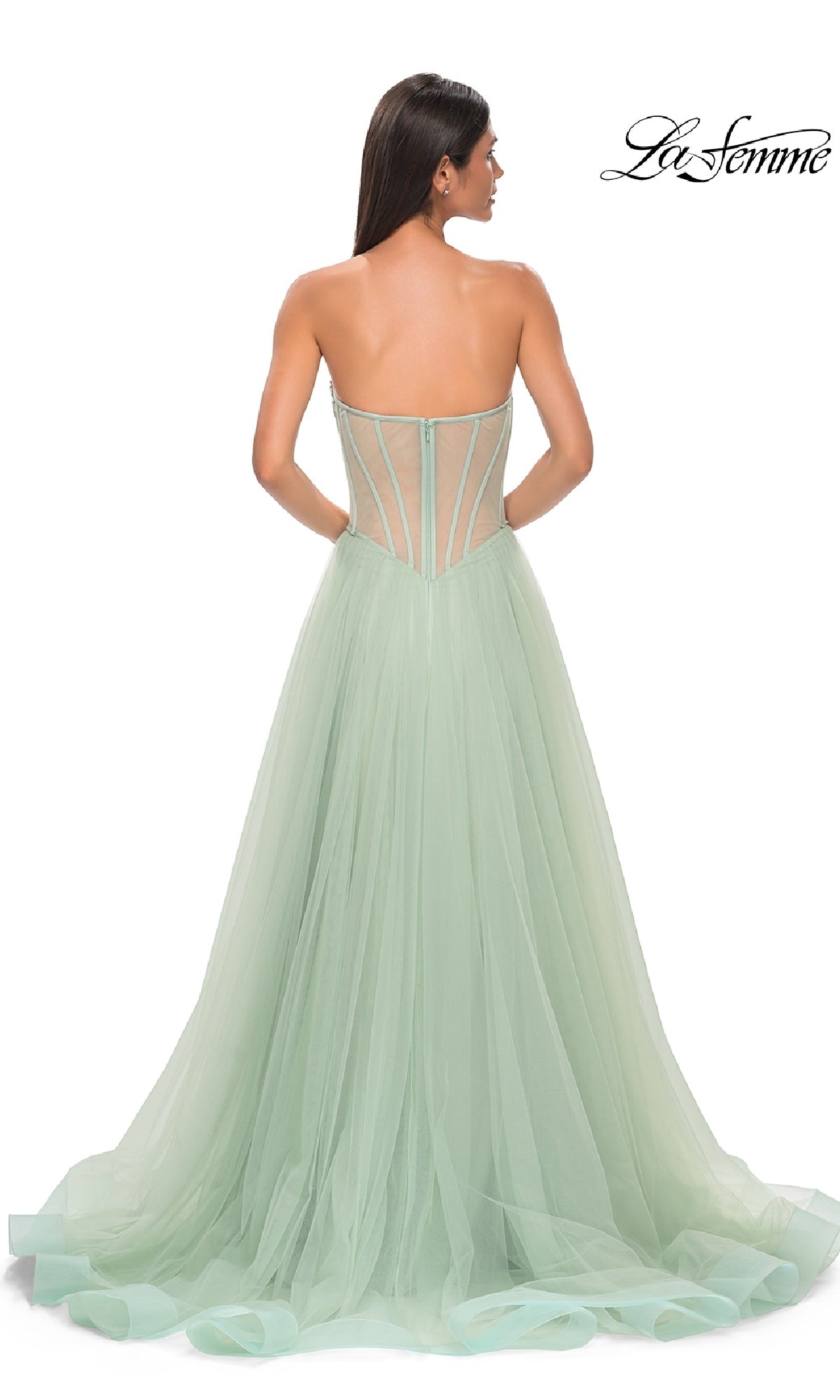 A woman faces away wearing the Strapless Long Prom Ball Gown: La Femme 32811, a light green a-line dress with a fitted beaded sweetheart corset bodice and sheer tulle skirt. The La Femme logo appears in the top right corner.
