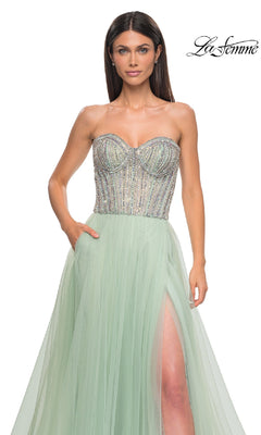 A woman wears the Strapless Long Prom Ball Gown: La Femme 32811, featuring a mint green beaded sweetheart corset bodice and thigh-high slit. The "La Femme" logo is in the top right corner.