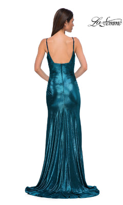 A woman stands facing away from the camera, wearing the La Femme 32812 V-Neck Long Metallic Prom Dress—a teal, floor-length gown with thin straps and a low back.