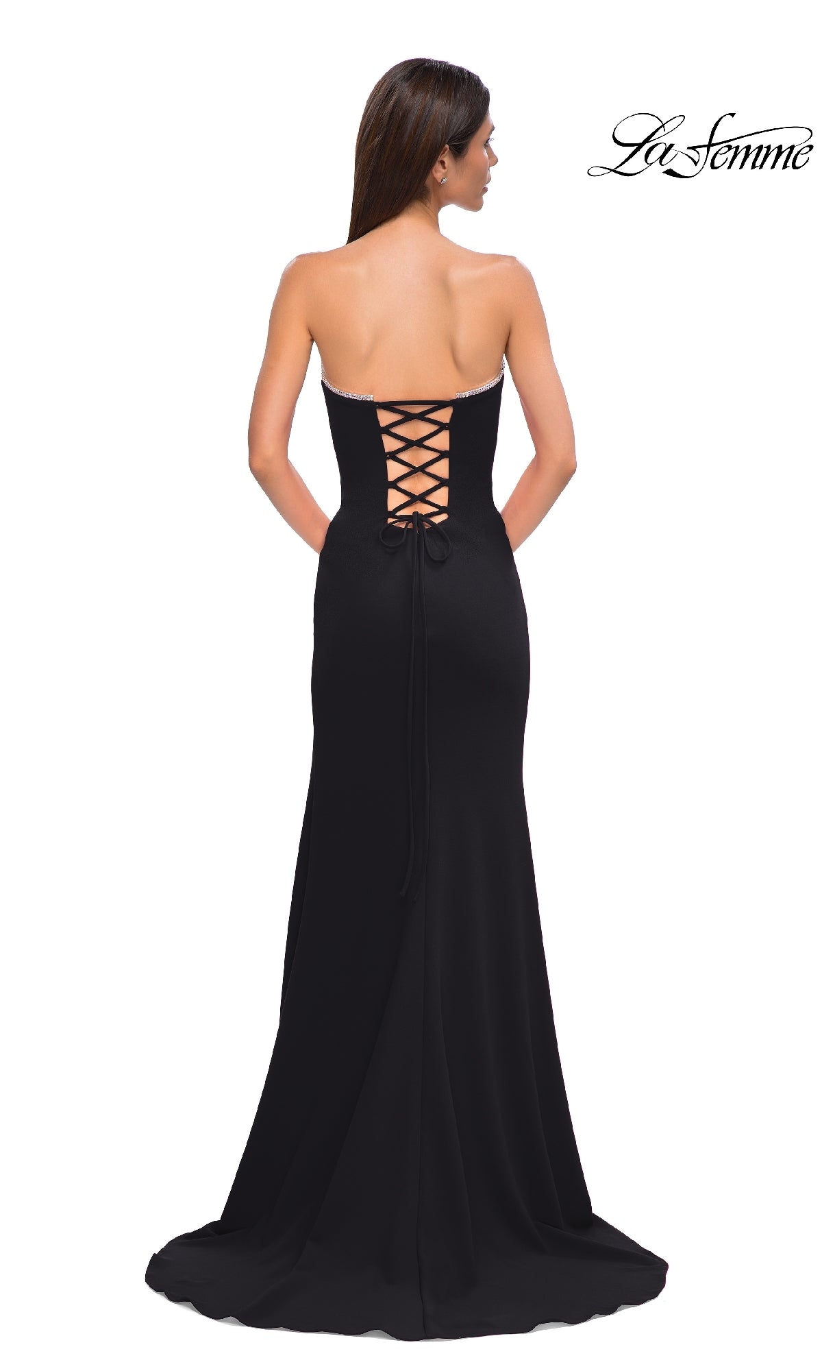 A woman stands facing away from the camera, wearing the Lace-Up Strapless Long Prom Dress: La Femme 32829, featuring a stylish lace-up back detail.
