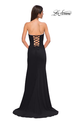 A woman stands facing away from the camera, wearing the Lace-Up Strapless Long Prom Dress: La Femme 32829, featuring a stylish lace-up back detail.