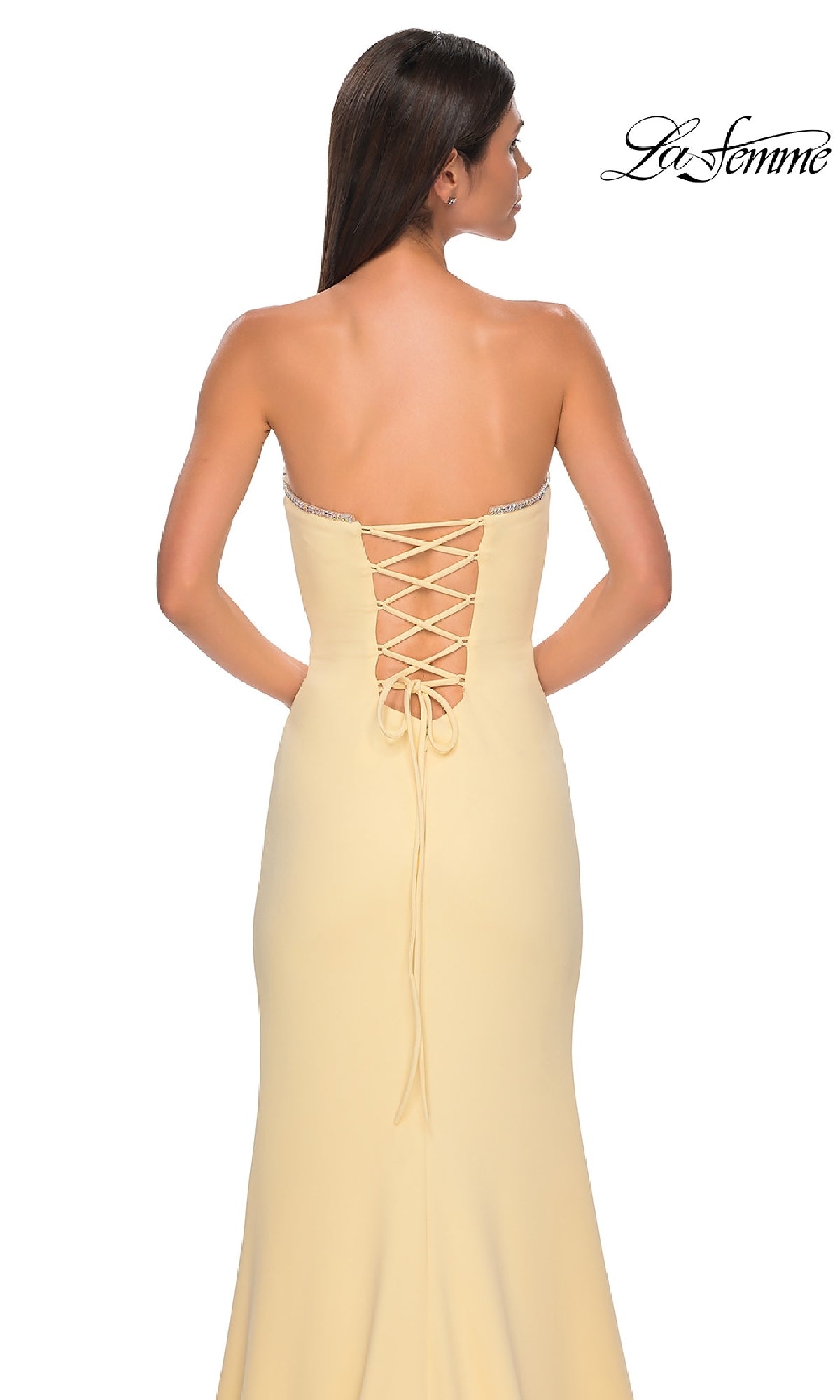A woman stands against a white background wearing the Lace-Up Strapless Long Prom Dress: La Femme 32829 in light yellow, featuring a lace-up back. The 