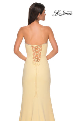 A woman stands against a white background wearing the Lace-Up Strapless Long Prom Dress: La Femme 32829 in light yellow, featuring a lace-up back. The "La Femme" logo appears in the top right corner.