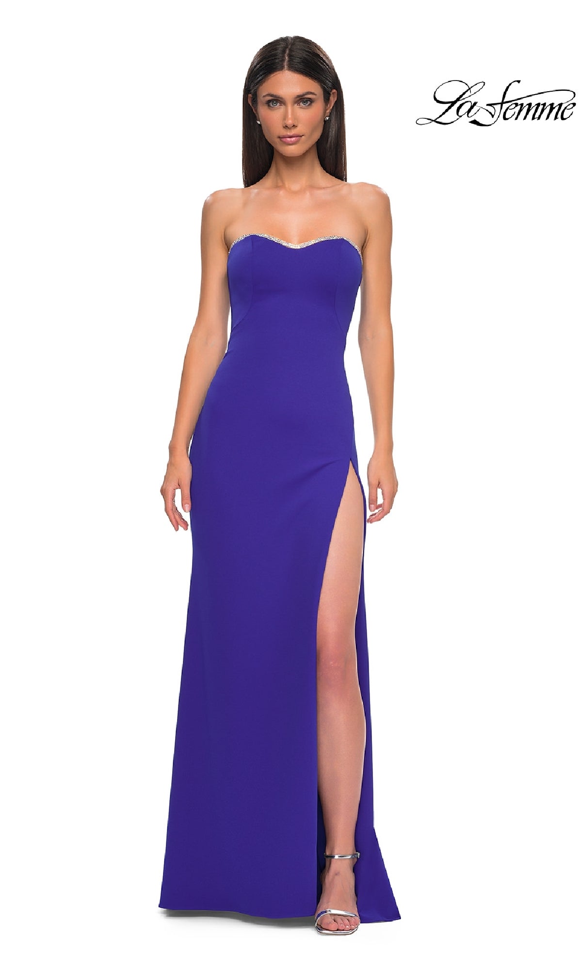 Woman in a strapless floor-length royal blue La Femme 32829 prom dress with lace-up back, high slit, and beaded trim, wearing silver heels against a plain background. 