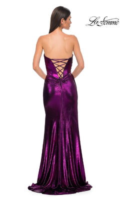 A woman stands with her back to the camera in La Femme 32830, a strapless long metallic prom dress with a lace-up back and a flowing, floor-length purple skirt.