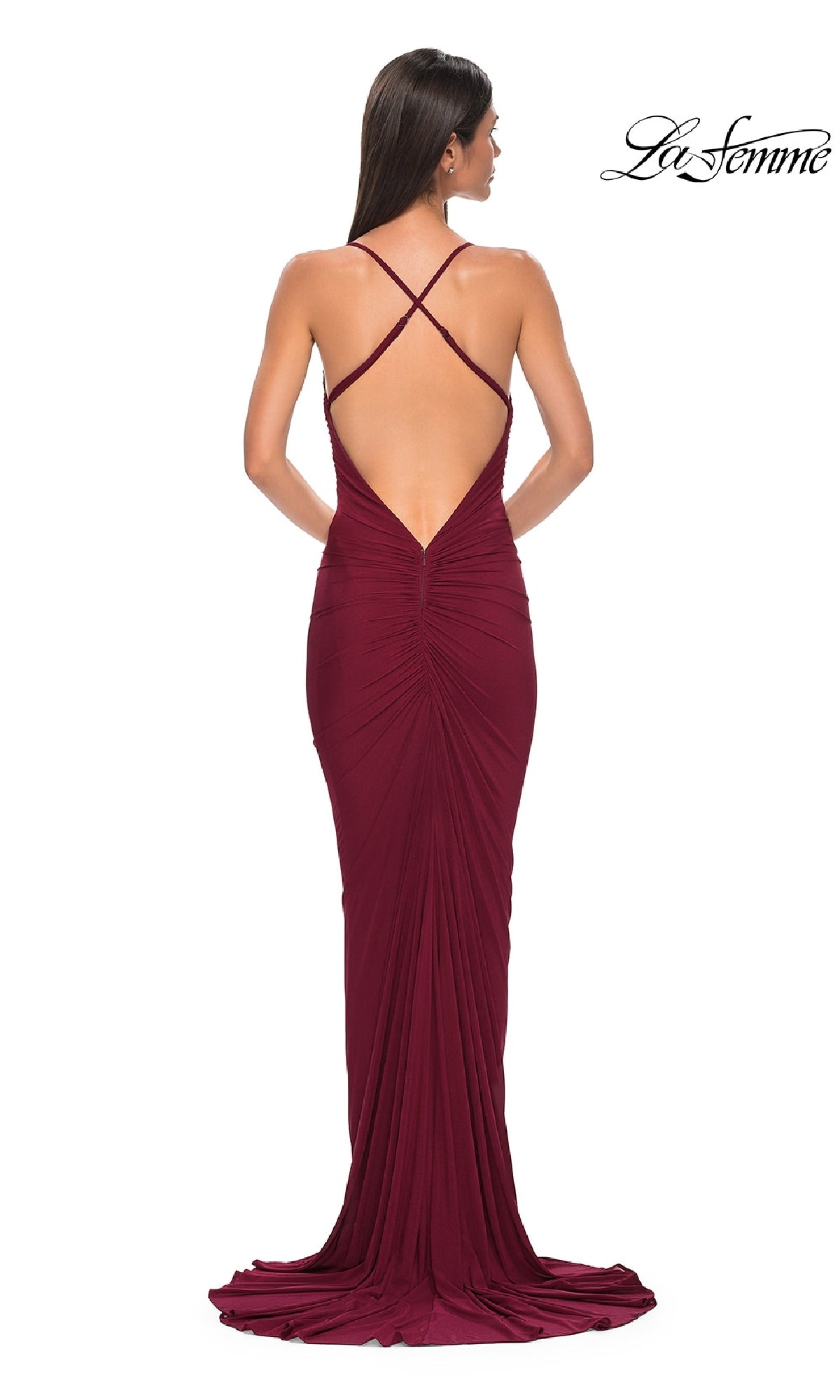 A woman stands facing away, showcasing the Deep V-Back Long Prom Dress: La Femme 32834—a floor-length burgundy gown with crisscross straps, cowl neck, low open back, and slight train—perfect for an elegant prom night.