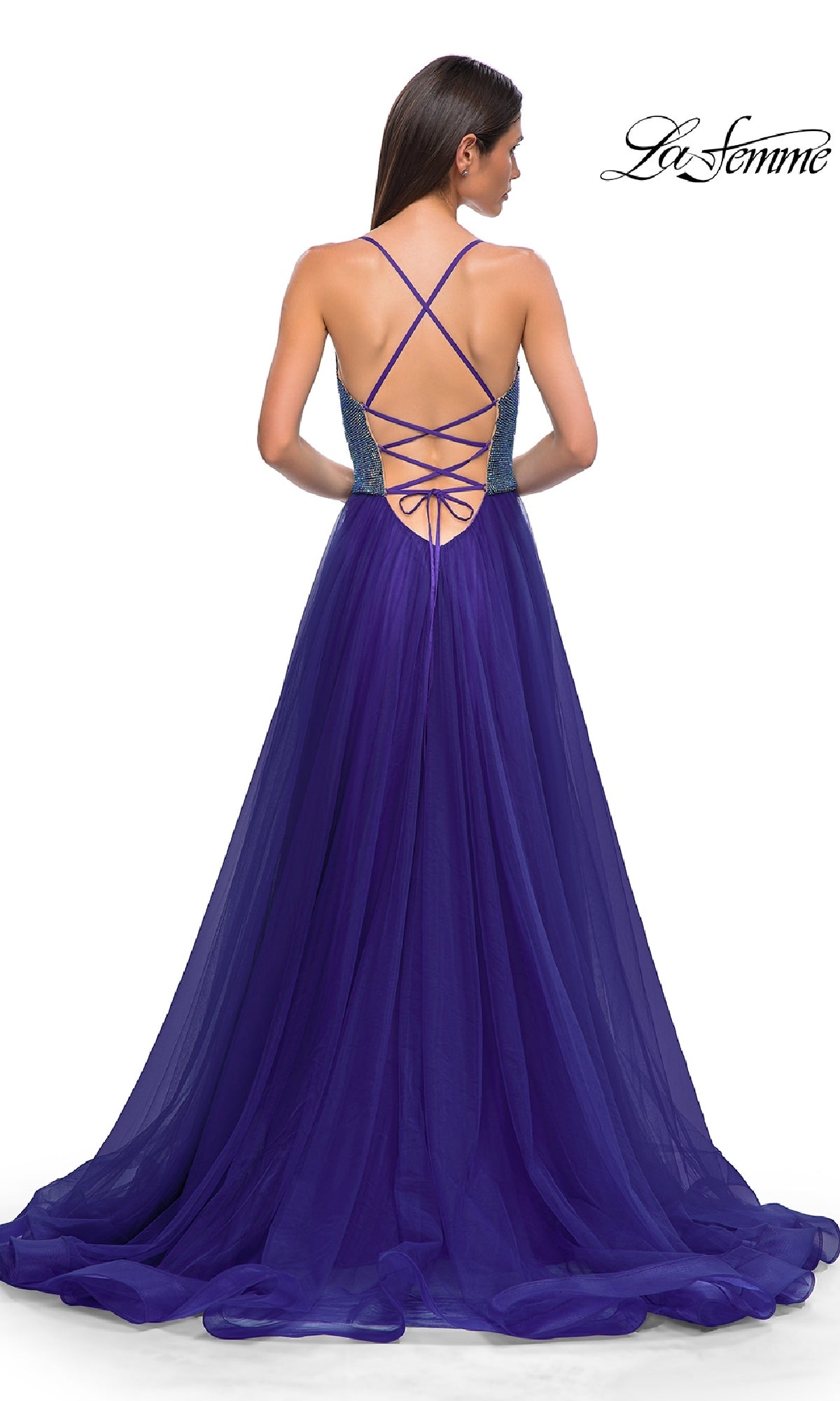 A woman wearing the La Femme 32838 Cowl-Neck Long Indigo Prom Dress stands with her back to the camera, showcasing its elegant cowl neckline and floor-length indigo design.