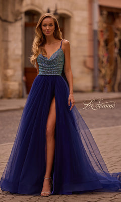 Wearing the La Femme 32838, a cowl-neck long indigo prom dress with a beaded bodice, thin straps, and high slit, she stuns on the cobblestone street.