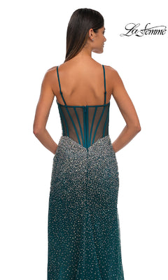Woman in a teal La Femme 32840 long beaded prom dress with thin straps, fitted bodice, and zip closure stands with her back to the camera. The elegant silhouette is highlighted. "La Femme" logo appears in the top right.