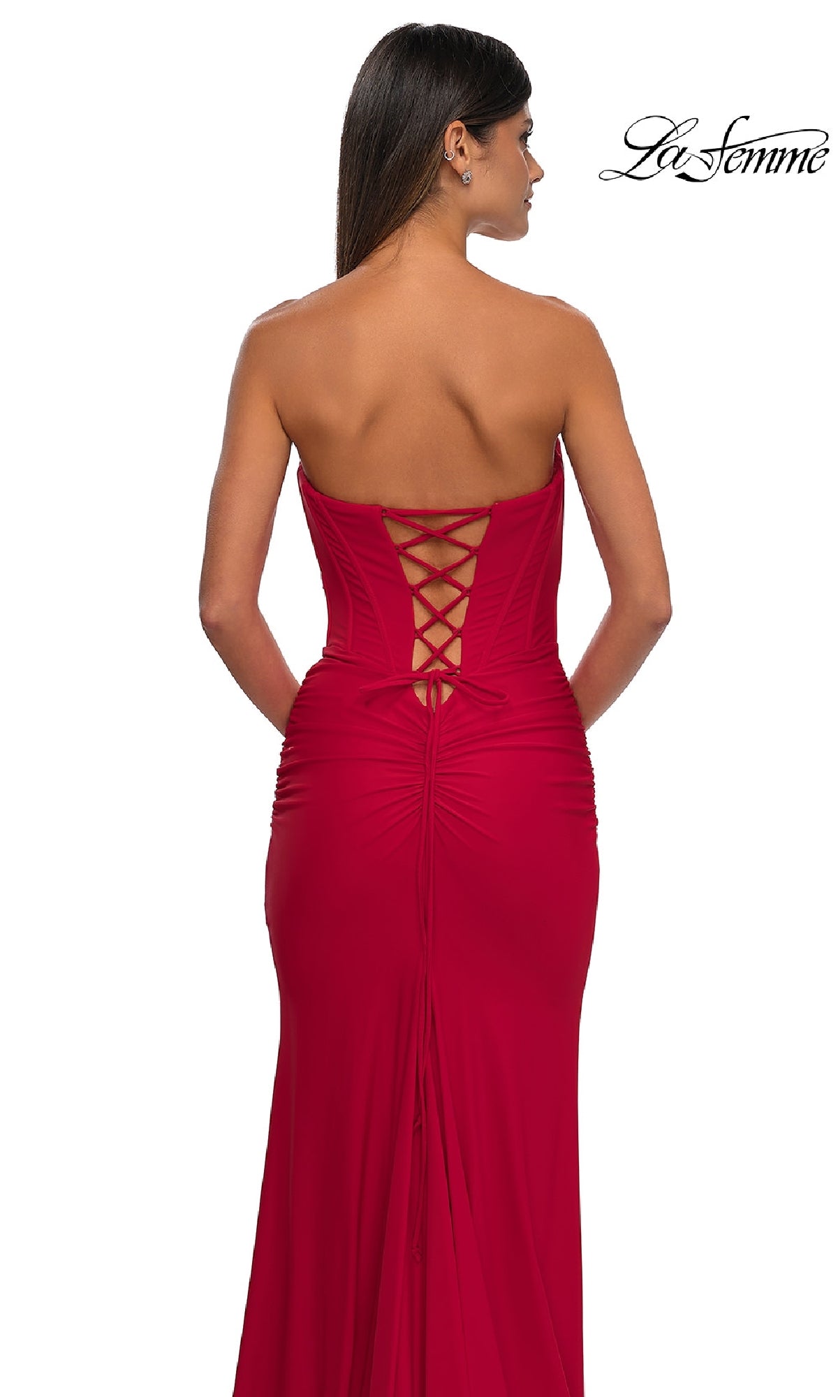 A woman models the Strapless Sweetheart Prom Gown: La Femme 32843, featuring a corset back, against a white background. The elegant design is showcased with 