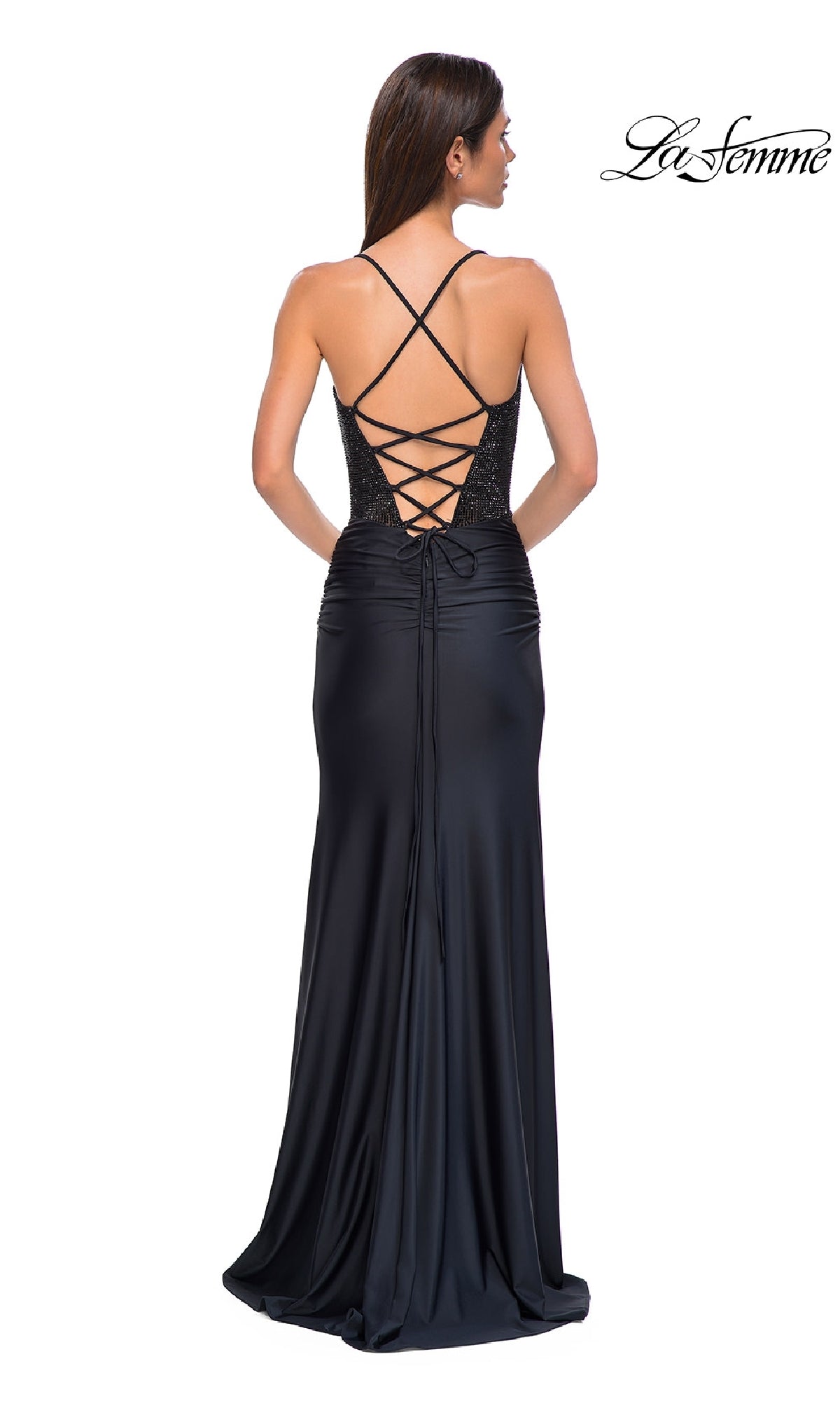 A woman stands facing away in the Strappy Long Black Prom Dress: La Femme 32845, featuring a beaded corset bodice, lace-up open back, and crisscross straps. The La Femme logo appears in the top right corner.