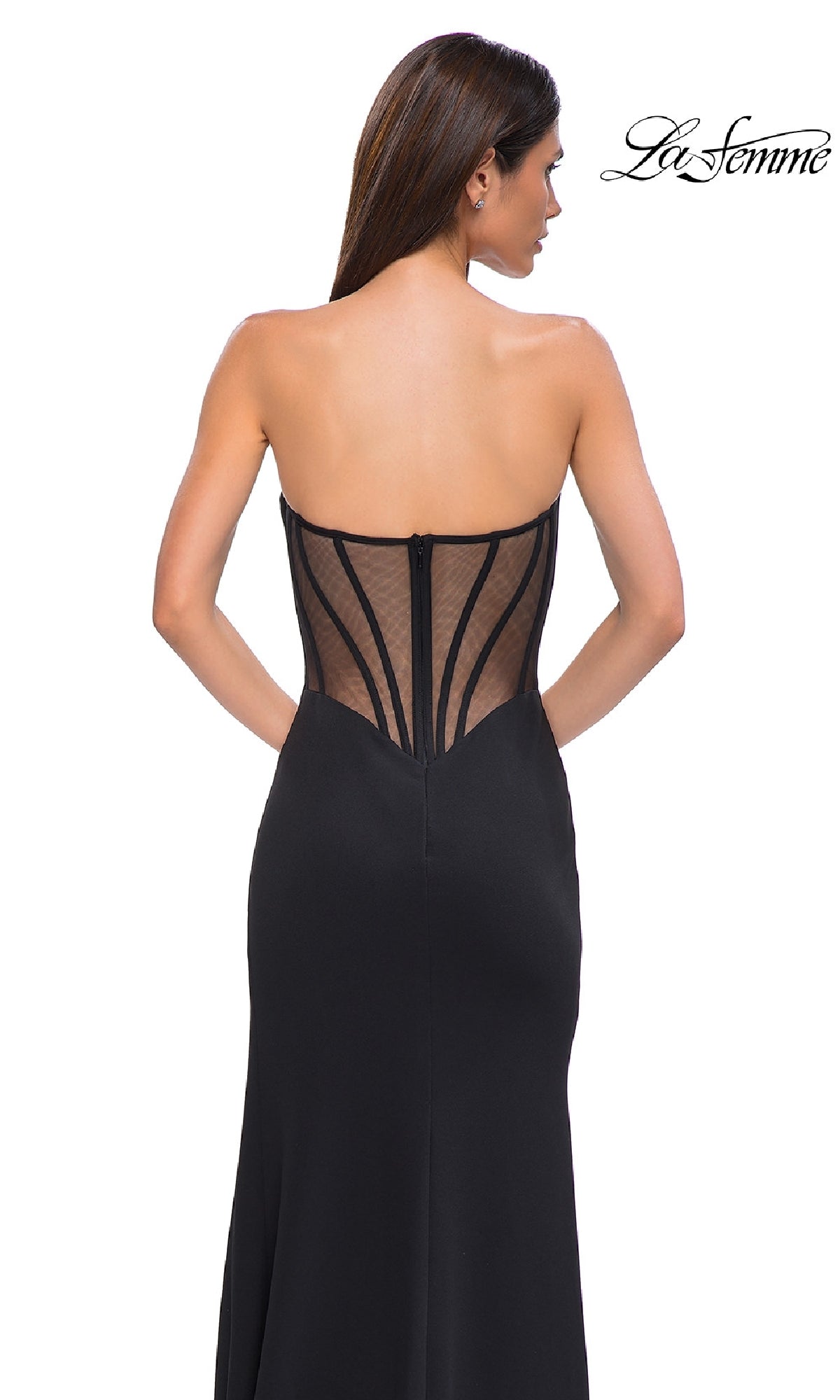 Woman wearing the Asymmetrical Strapless Prom Gown, La Femme 32849, featuring a sheer mesh back and visible boning, poses against a white background. The 