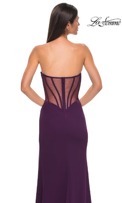 A woman wears the La Femme 32849 Asymmetrical Strapless Prom Gown in purple, featuring a sheer corset back with visible boning, shown from behind. The La Femme prom dress logo is displayed in the top right corner.