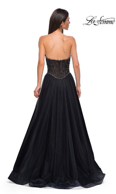 A woman stands with her back to the camera in the Strapless Long Black Prom Ball Gown: La Femme 32856, featuring a beaded bodice and full floor-length skirt against a plain white background.