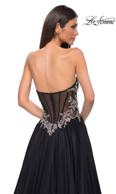 Woman wearing the La Femme 32862 Beaded-Corset Strapless Prom Gown with a sheer, beaded corset-style back and floral embroidery, standing against a white background.