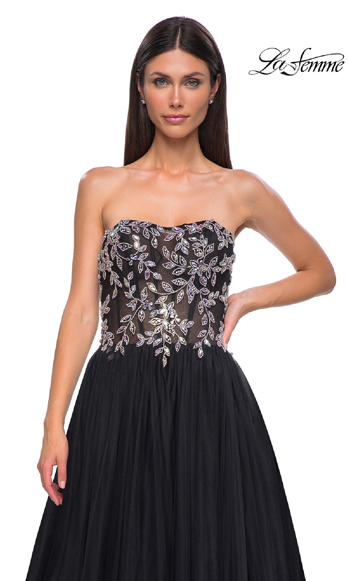 A woman wears the Beaded-Corset Strapless Prom Gown (La Femme 32862), featuring a beaded leaf-pattern corset bodice and flowing tulle a-line skirt. 