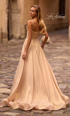 A woman in the La Femme 32864 Long Metallic Chiffon Prom Dress stands on a cobblestone street, glancing over her shoulder. The "La Femme" logo is displayed in the top right corner.