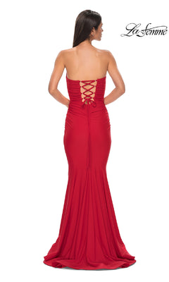 Woman wearing the Lace-Up Strapless Long Prom Dress: La Femme 32872, in red with a lace-up back, stands facing away from the camera; "La Femme" logo appears in the upper right corner.