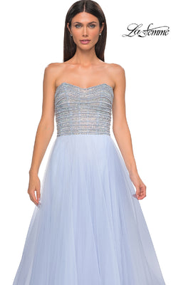 A woman wears the Strapless Long Prom Ball Gown: La Femme 32875 in light blue, featuring a beaded bodice and flowing tulle skirt, standing against a plain white background. The "La Femme" logo is shown in the top right corner.