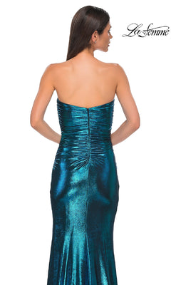 A woman wearing the Bodycon Long Metallic Prom Dress: La Femme 32876, featuring a strapless sweetheart neckline and ruched back detailing, stands facing away from the camera.