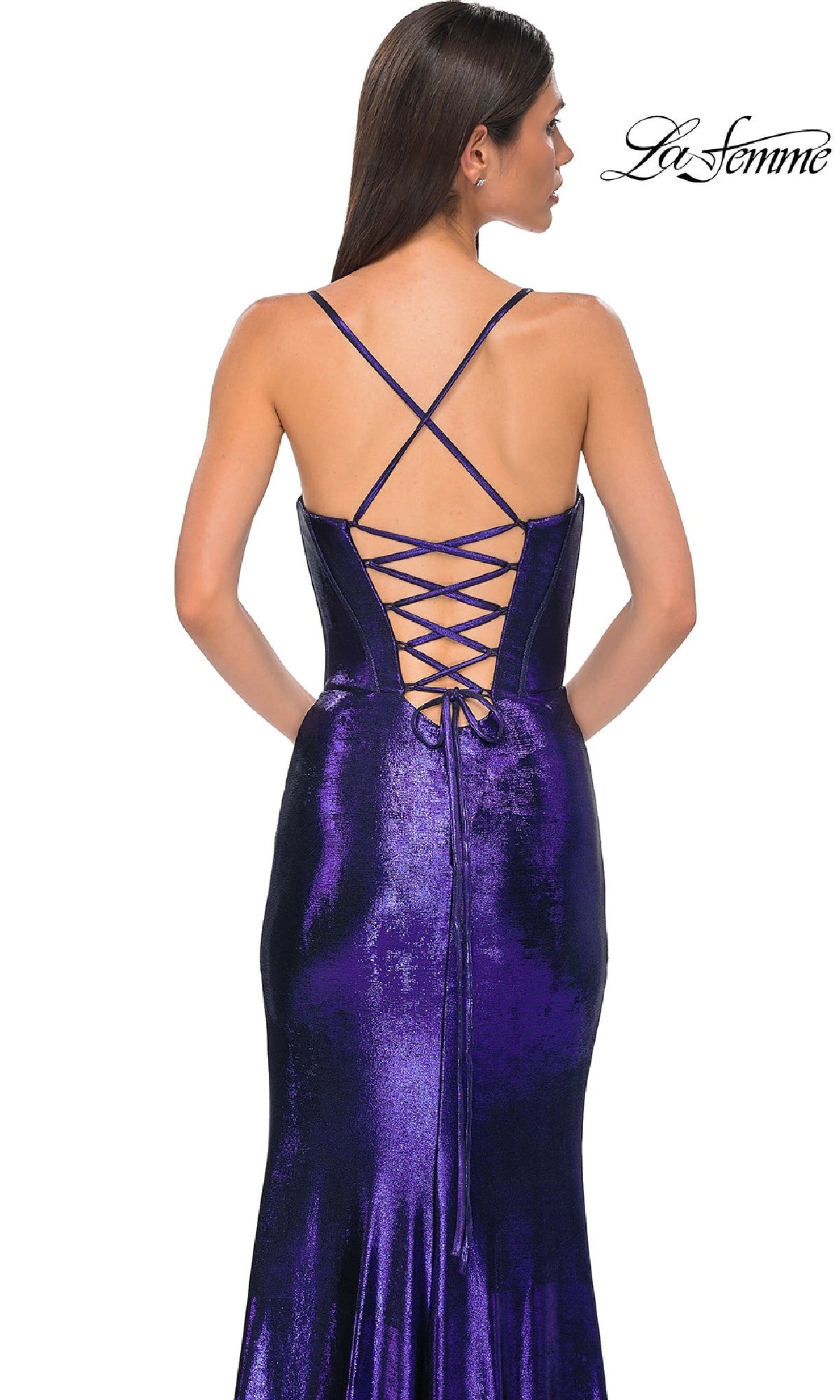 A woman faces away in the La Femme 32877 Lace-Up Long Metallic Prom Dress, a shiny purple designer gown with thin cross straps and a lace-up back. The La Femme logo is displayed in the top right corner.