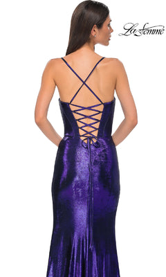 A woman faces away in the La Femme 32877 Lace-Up Long Metallic Prom Dress, a shiny purple designer gown with thin cross straps and a lace-up back. The La Femme logo is displayed in the top right corner.