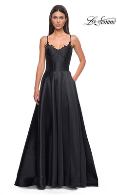 A woman models the La Femme 32878 Lace-Up Long Mikado Prom Dress, a black satin floor-length gown with thin straps and a fitted bodice, standing against a white background with the La Femme logo in the top right corner.
