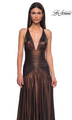 A woman models the La Femme 32887 long prom dress—sleeveless, metallic, with a deep V-neck and open back—standing before a plain white background. The "La Femme" logo appears in the top right corner.