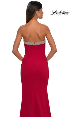 A woman with long dark hair and simple earrings is seen from the back wearing the Bead-Trimmed Long Prom Dress: La Femme 32891, a strapless formal gown featuring a jeweled band along the top for a stunning prom look.