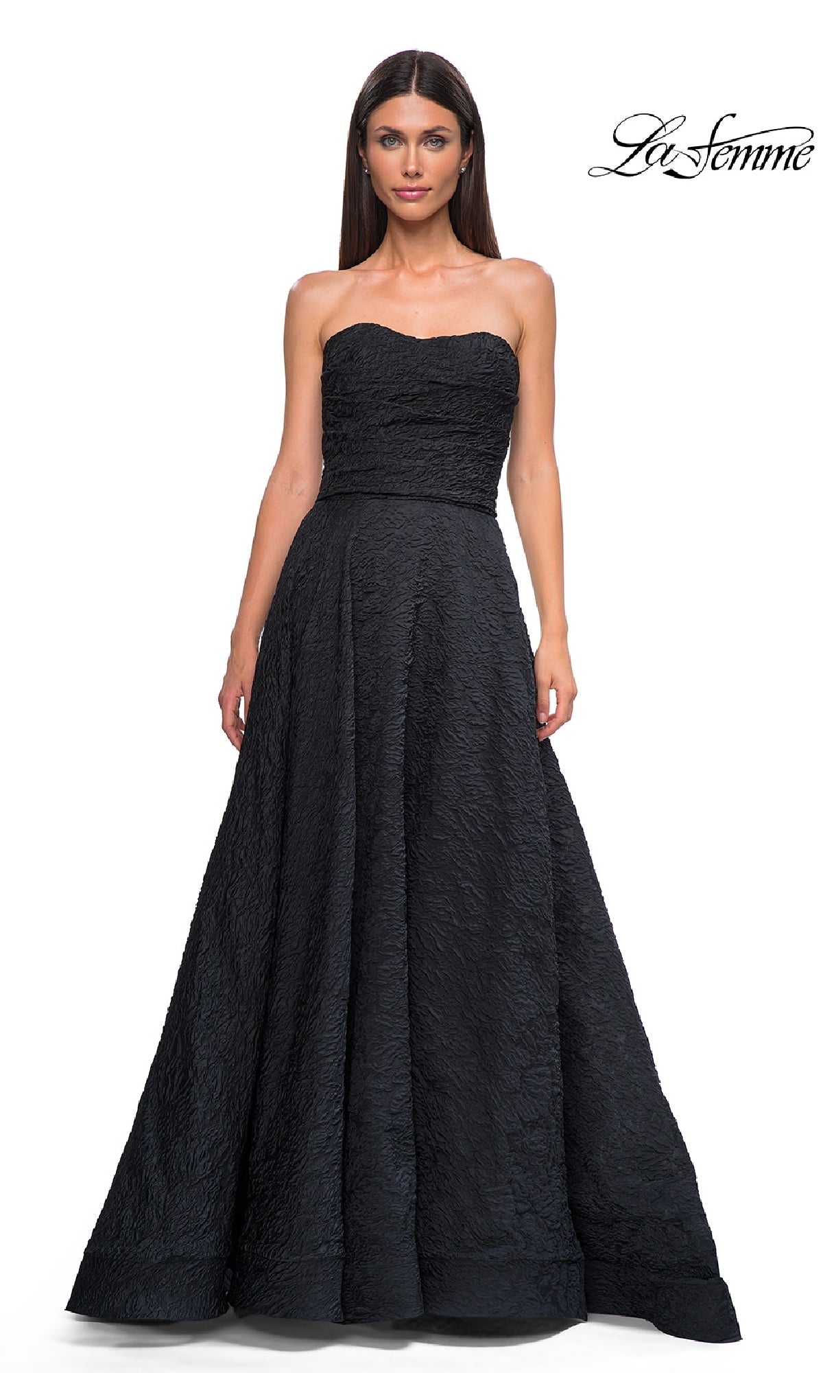 A woman models the La Femme 32893 Textured Strapless Black Prom Dress, featuring a fitted bodice and full skirt, against a white backdrop with the 