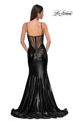 A woman faces away in the Long Metallic Mermaid Prom Dress: La Femme 32897. The black, floor-length gown has thin straps, a semi-sheer back, and a shiny metallic finish. The "La Femme" logo is in the upper right corner.