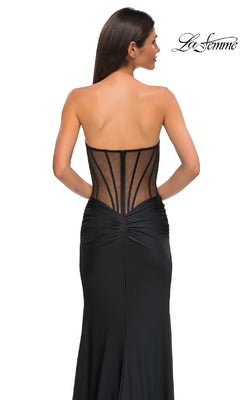 A woman wears the Sheer-Waist Long Corset Prom Dress: La Femme 32912, featuring a strapless design, sheer corset-style back with visible boning, and elegant beaded lace details. The La Femme logo appears in the top right on a white background.