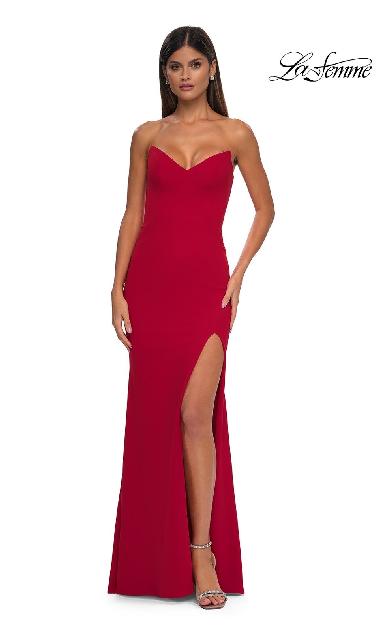A woman models the Strapless Sweetheart Prom Dress: La Femme 32919, featuring a fitted red silhouette and high slit, standing against a white background with the 
