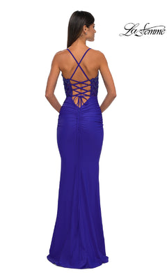 Woman in a floor-length La Femme 32920 beaded-bodice long prom dress stands with her back to the camera, featuring elegant ruching and a crisscross lace-up back.