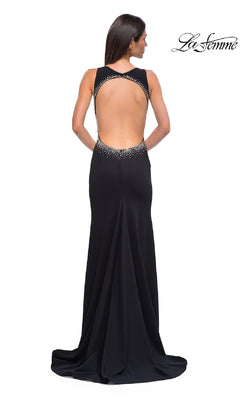 A woman stands with her back to the camera in the La Femme 32922 long black jersey prom dress, featuring an open back and rhinestone details. The "La Femme" logo appears in the top right corner.