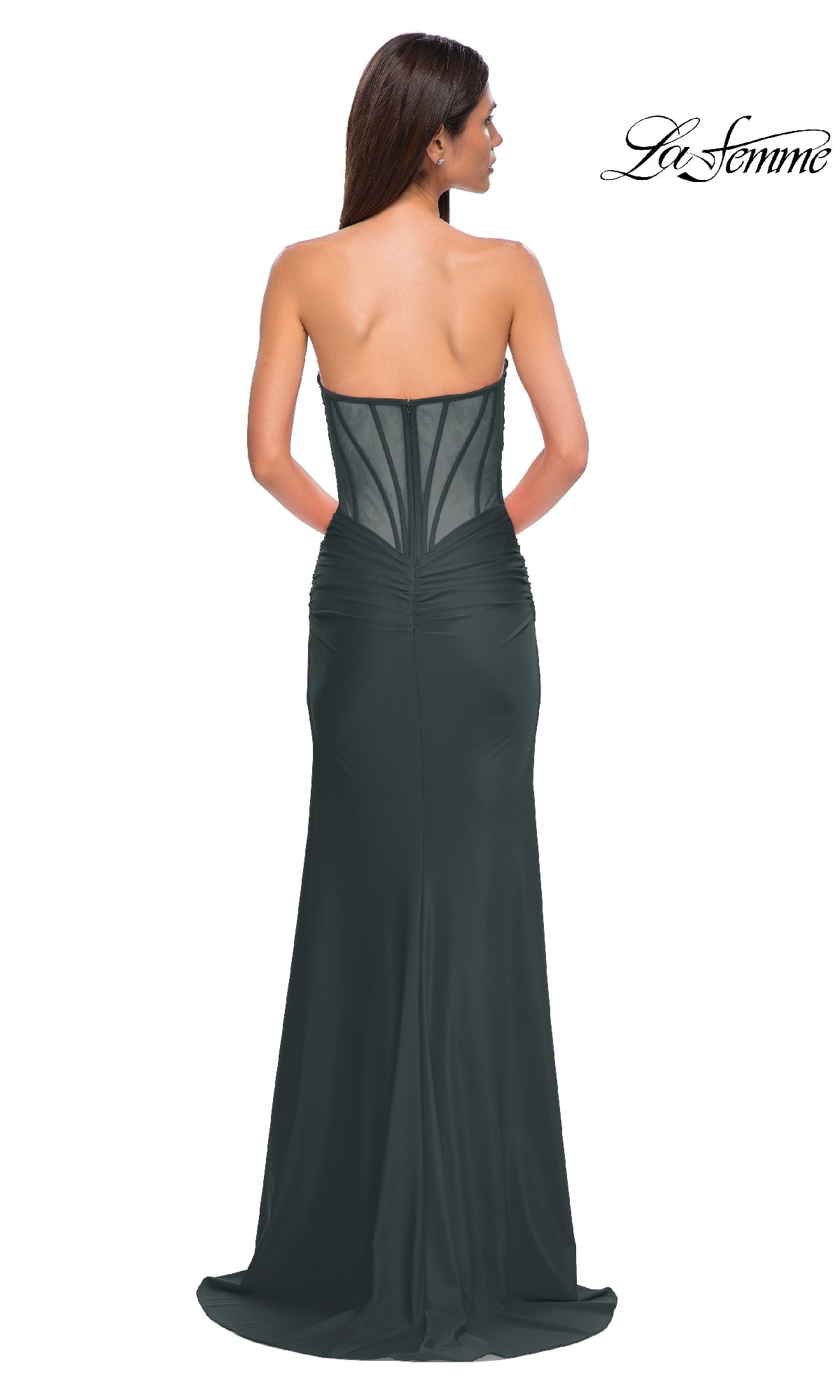 A woman models the Sheer-Back Long Prom Dress: La Femme 32923, featuring a strapless design and corset-style sheer back. The floor-length black formal gown highlights her elegant silhouette as she faces away from the camera.