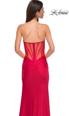 A woman is seen from the back wearing the La Femme 32923 Sheer-Back Long Prom Dress, a strapless red gown featuring a fitted silhouette, sheer panel with visible boning on the bodice, and gathered waist detailing for elegance.