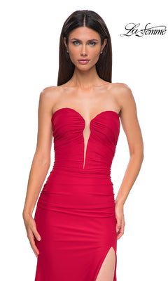 A woman wears the La Femme 32923: a strapless, ruched red long prom dress with a deep V-neckline and high slit, featuring a sheer back, standing before a white background with the "La Femme" logo in the top right corner.