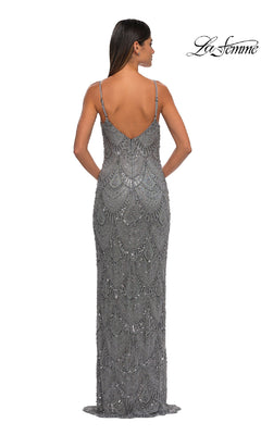 A woman stands facing away in the Vintage Long Beaded Prom Dress: La Femme 32928, a floor-length silver sequin gown with thin straps and an intricate pattern, radiating timeless elegance.