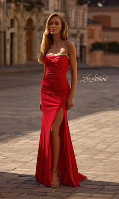 A woman wearing the La Femme 32931 Lace-Up Strapless Long Prom Dress with a rhinestone sweetheart neckline and thigh-high slit stands on a cobblestone street, with the "La Femme" logo displayed in the image.
