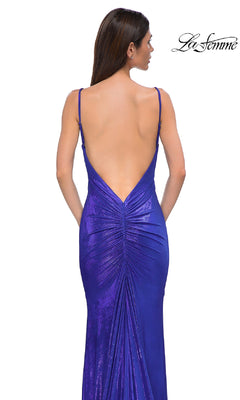 A woman with long brown hair models the La Femme 32932, a backless metallic purple prom dress with thin straps, ruching at the back seam, and a mermaid skirt as she faces away from the camera.