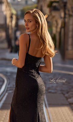 Woman with long blonde hair in the La Femme 32933 Long Beaded-Lace Prom Dress stands on a city street with tram tracks, glancing back over her shoulder.