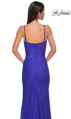 A woman models the Long Beaded-Lace Prom Dress (La Femme 32933) in fitted royal blue with thin straps, viewed from the back on a white background. The La Femme logo appears in the top right corner.
