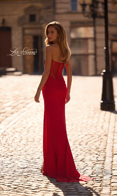 A woman in the La Femme 32941 Strapless Deep V-Neck Prom Gown stands on a sunlit cobblestone street, looking back over her shoulder.