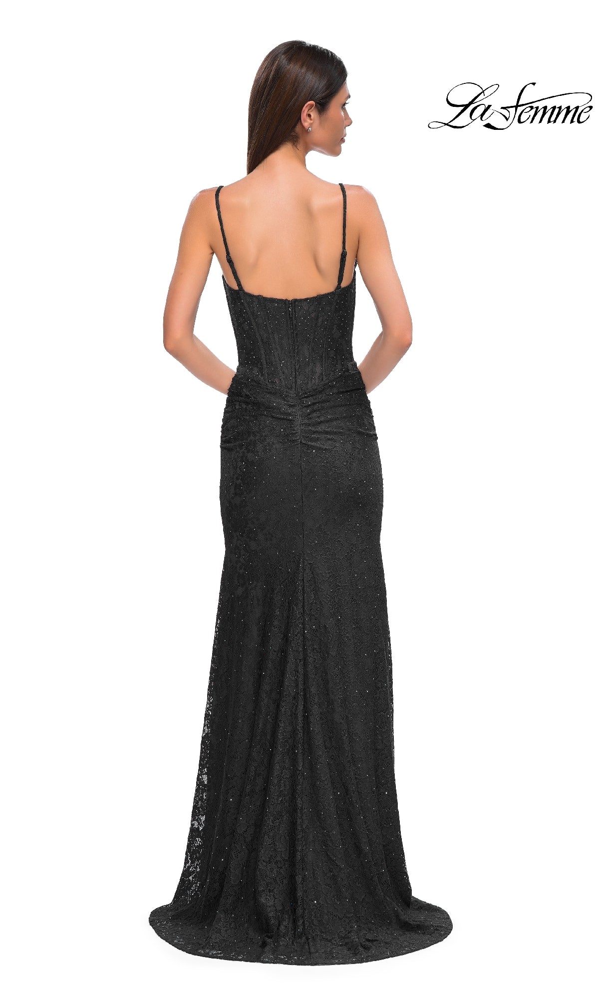 Woman modeling the Sheer-Waist Long Beaded Prom Dress (La Femme 32947), a fitted black lace gown with thin straps, shown from the back against a white background. The 