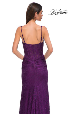 A woman wearing the Sheer-Waist Long Beaded Prom Dress (La Femme 32947), a sleeveless, floor-length purple lace gown, is shown from the back against a plain white background.