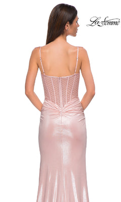 A woman models the La Femme 32951 long prom dress—a shimmery light pink, fitted gown with thin straps, visible seams, and a high leg slit—shown from the back against a plain white background.