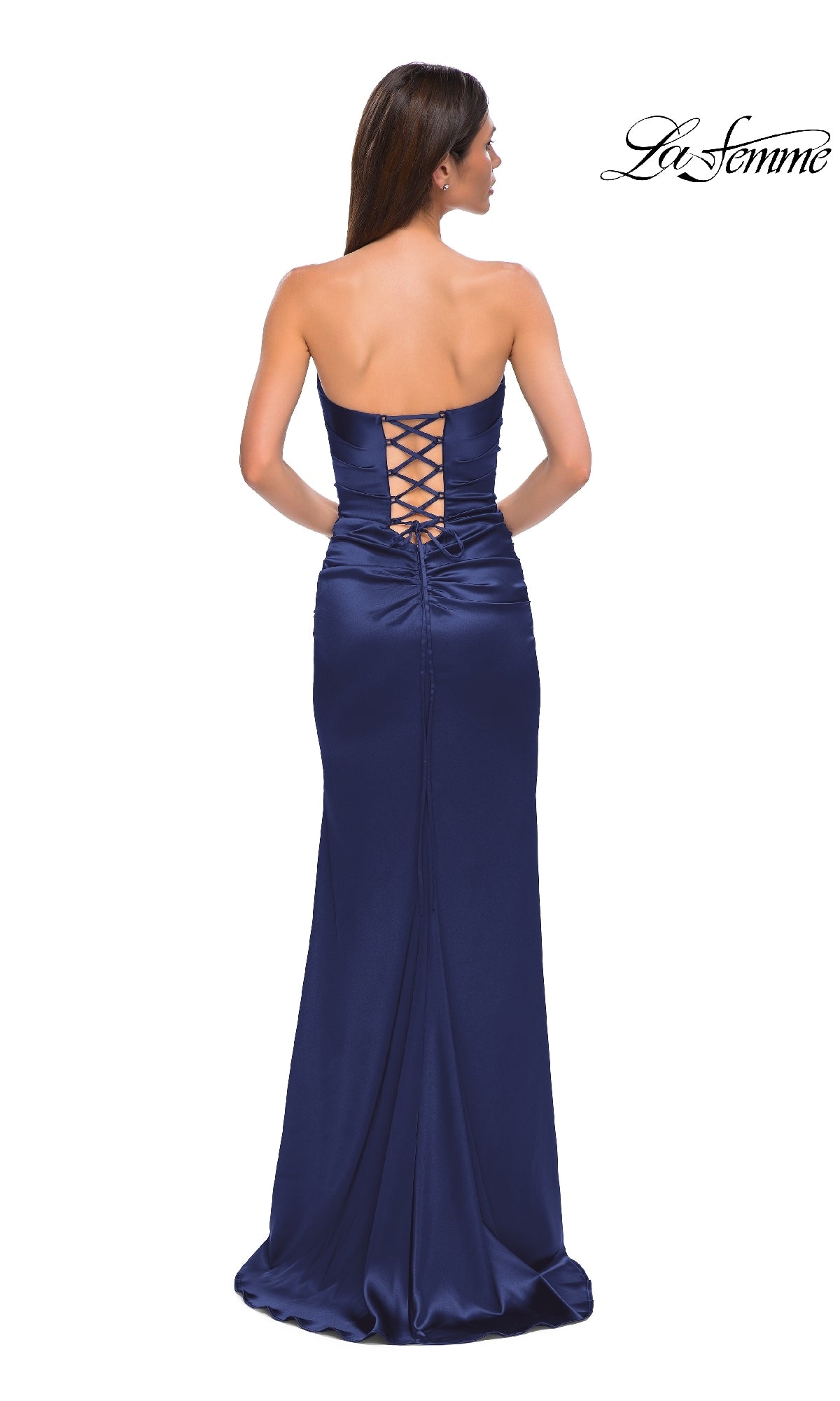 A woman stands facing away from the camera in the La Femme 32952 strapless long satin prom dress, showcasing its lace-up back and slight train.