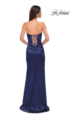 A woman stands facing away from the camera in the La Femme 32952 strapless long satin prom dress, showcasing its lace-up back and slight train.