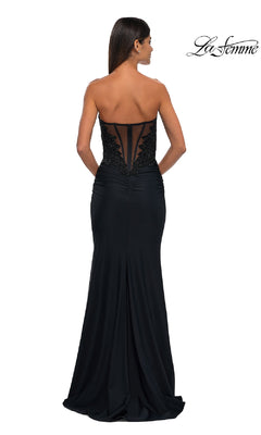 A woman models the Strapless Sweetheart Prom Gown: La Femme 32961, showcasing lace and mesh back detailing and a beaded corset bodice, against a white background. "La Femme" logo appears in the top right corner.